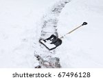 after a heavy snowstorm. black shovel to remove the snow from the garden path.