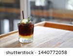 Iced coffee with lemon - A glass of espresso shot mixed with lemonade juice and honey, topped with sliced lime and rosemary leaves on blurred background and copy space, Perfect drink for summer time.