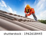 Builders in work clothes install new roofing tools, roofing tools, electric drill and use them on new wooden roofs with metal sheets