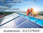 Small photo of Technician inspecting solar panel maintenance on hospital roof, solar panel maintenance view
