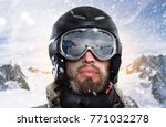 portrait of a snowboarder with helmet and goggles in front of sunrise in wintry mountains landscape while a stormy blizzard