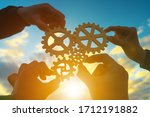 Small photo of Four hands of businessmen collect gear from the gears of the details of puzzles. against the background of sunlight. The concept of a business idea. Teamwork. strategy. Collaboration, partnership