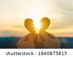 Small photo of Two hands hold a broken heart on the background of the sunset. Concept spat divorce dissolution, love feelings
