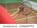The badminton player's hand holds the strings of the racket