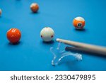 portrait of the cue stick poking the white ball helped by the bridge at the billiard game