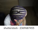 Small photo of The master demonstrates to students how to weave an African braid with Kanekalon on a model, afro-locks on a frame, frame hairstyles, afro-curls, a base for hair extensions, a thin braid braided over