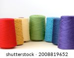 Spools of rainbow colors wool yarn for hand and machine knitting on a white background