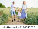 Happy family walking along the wheat field at summer day. The concept of family and love. Slow motion, relax, happy childhood.