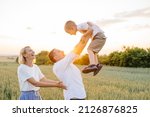 Happy family, middle age mother, father and their little sun having fun at the wheat field. Help and support concept for children.