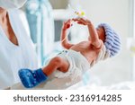 Small photo of Premature baby hand with a catheter. Unrecognizable female nurse wearing uniform with premature born baby in intensive care unit holding cute infant in her hands.