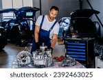 Small photo of Electric car engine removed from car for repair. Arabian man use voltmeter working Internal Permanent Magnet Synchronous Reluctance Motor. Service maintenance of industrial to engine repair.