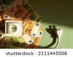 White socket and electric power supply power cords plug with Euro banknotes on green background. Increasing cost of electricity, expensive energy concept