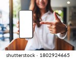Mockup image of a beautiful woman pointing finger at a mobile phone with blank white screen 