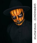 Small photo of Halloween. Close-up portrait of a devilish handsome man with skull makeup on a dark background.