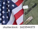 Military dog tag token and knife lies on Old US Coast Guard uniform and folded United States Flag