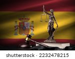 Small photo of Spain flag with statue of lady justice, constitution and judge hammer on black drapery. Concept of judgement and punishment