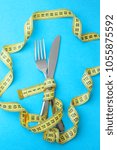 Small photo of Fish Day diet for weight loss. Fork and knife are wrapped in yellow measuring tape on blue background