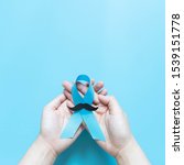 Small photo of Men's health and Prostate cancer awareness campaign in November. Man hands holding light blue ribbon awareness w/ mustache on blue background. Symbol for support men who living w/ cancer. Copy space.
