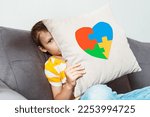 Small photo of Kid boy holding pillow with puzzle heart, child mental health concept, world autism awareness day, teen autism spectrum disorder awareness concept