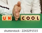 Small photo of A man separates the cubes with the inscription - UNCOOL or COOL.