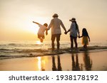 Happy asian family jumping together on the beach in holiday. Silhouette of the family holding hands enjoying the sunset on the  beach.Happy family travel and vacations concept. 