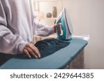 Small photo of clothes, appliance, home, housework, iron, ironing, laundry, steam, clean, domestic. close-up of ironing clothes on an ironing board after then young women is going to folding clothes on that.