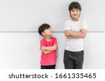Little child boy standing arms crossed and looking face of tall child at standing arms crossed and smiling. Big and small kid concept at be friends.