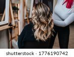 Beautiful hairstyle of young woman after dyeing hair and making highlights in hair salon.