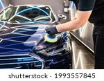 Car detailing - Man with orbital polisher in repair shop polishing car. Selective focus.	