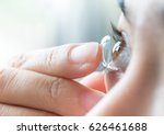 Young woman putting contact lens in her right eye, close up