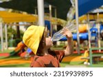 Small photo of A cute boy drinks water from plastic bottle. Summer thirst, preschooler drinking water on a hot day