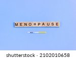 Small photo of Word Menopause on wooden blocks with lettering and rapid FSH test. Concept of female periods. Copy space