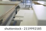 Small photo of The craftsman is sanding a wooden part. Furniture manufacture. Wood furniture sanding. A worker is sanding a wooden part at a furniture factory. Furniture manufacturing process