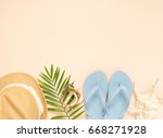 Summer fashion, summer outfit on cream background. Blue flip flops, seashell, wood bracelet and straw hat. Flat lay, top view