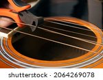 Guitar restring: musician cut strings from an acoustic guitar
