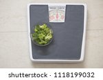 Bowl of fresh broccoli on bathroom scale, diet food concept