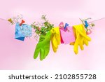 Creative bright spring cleaning concept. Tools, bottles, accessories for cleaning house with spring flowers and leaves hang on clothesline, box, bright sunny light copy space 