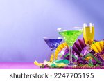 Small photo of Mardi gras cocktails set. Colorful purple, yellow, green martini champagne wine cocktail glasses for Mardi gras party bar with carnival decor and orleans masquerade masks