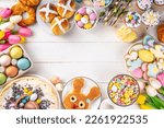 Small photo of Easter brunch, breakfast food, Kids Easter party buffet. Various traditional Easter sweets, candy, pasties and baking - cross buns, cheesecake, chocolate eggs, pancakes, cupcakes, top view copy space