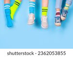 Small photo of Odd Socks Day, Lonely Sock Day. Anti-Bullying Week, Down syndrome awareness. Child legs wearing different pair of mismatched socks on high-colored background copy space