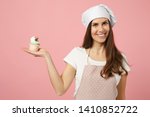 Cute housewife chef cook confectioner baker in white t-shirt, toque chefs hat cooking hold sweet isolated on pink pastel background in studio. Cupcake making process. Mock up copy space food concept