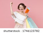 Happy young woman girl in summer clothes isolated on pink background studio. Shopping discount sale concept. Mock up copy space. Hold package bag with purchases, passport tickets doing winner gesture