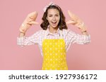 Small photo of Funny young woman housewife in yellow apron gloves potholders showing blah blah gesture ja jaja hands while doing housework isolated on pastel pink background studio portrait. Housekeeping concept