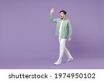 Small photo of Full length side view smiling caucasian man 20s wearing casual mint shirt white t-shirt walking going waving hand say hello isolated on purple color background studio portrait People lifestyle concept