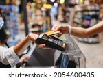 Small photo of Cropped close up woman hand arm shopping at supermaket put credit card to wireless modern bank payment terminal process acquire payments near cashier checkout inside store. People purchasing concept