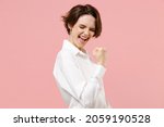 Small photo of Young fun overjoyed successful employee business woman corporate lawyer 20s in classic formal white shirt work in office do winner gesture clench fist say yes isolated on pastel pink background studio