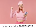 Small photo of Young happy woman with bright dyed rose hair in rosy top shirt hat hold in hand use mobile cell phone do winner gesture isolated on plain light pastel pink background People lifestyle fashion concept.