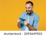 Small photo of Gambling young happy man 20s wearing blue shirt white t-shirt using play racing app on mobile cell phone hold gadget smartphone for pc video games isolated on plain yellow background studio portrait.