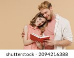 Young smiling happy parent man have fun with child teen girl in casual pastel clothes Daddy little kid daughter reading book together isolated on beige background. Father's Day Love family concept.