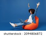 Small photo of Full body overjoyed young smiling student happy black woman in casual clothes shirt white tshirt sit in bag chair hold use work on laptop pc computer finish job isolated on plain dark blue background.